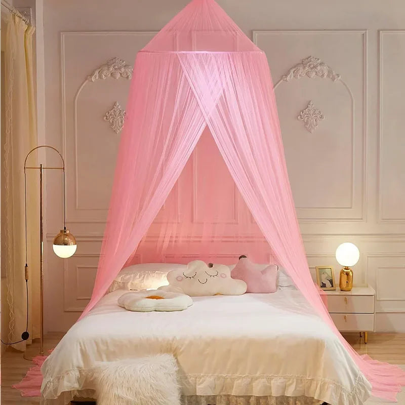 A pink ceiling-hung dome mosquito net draped over a bed in a light-colored room.