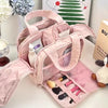 A pink travel makeup bag with a wide opening is shown, containing various cosmetics and tools.