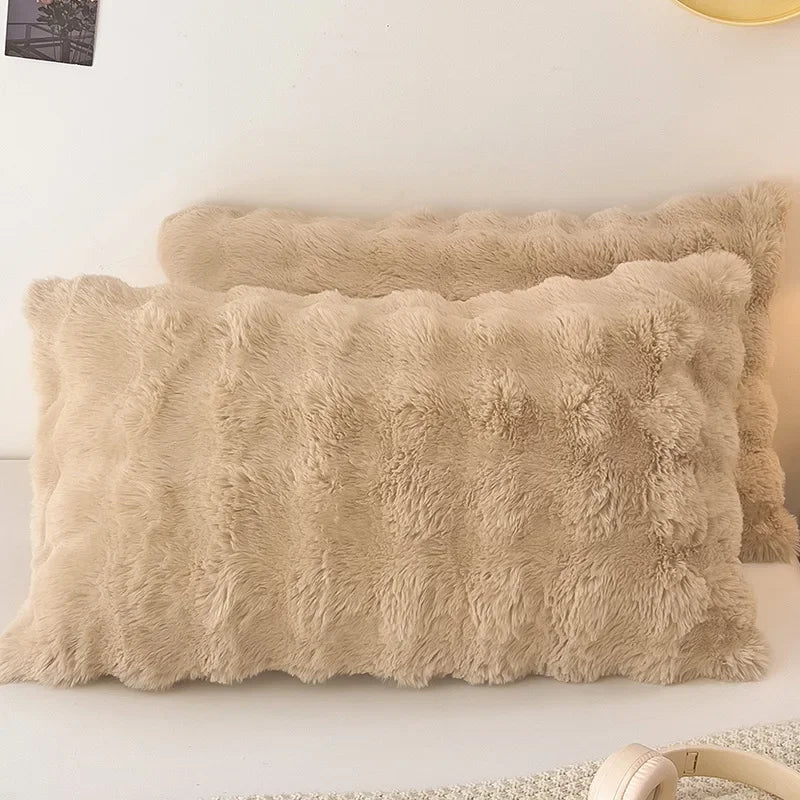 A fluffy beige quilted velvet pillow is displayed on a white surface.