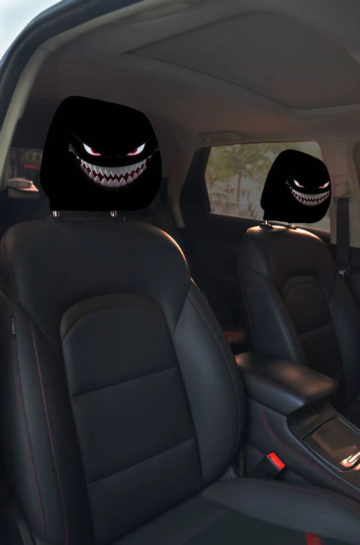A pair of horror-themed car headrest covers featuring creepy face designs on black leather seats.