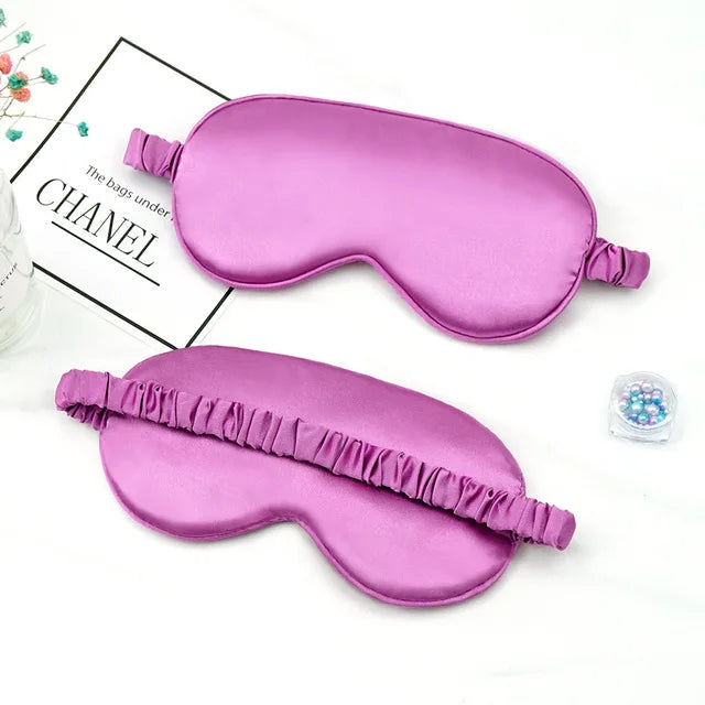 A pink silk sleep mask with a ruffled edge is shown next to a box labeled Chanel.