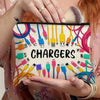 A hand holds a canvas charger storage pouch filled with various electronic chargers and cables.