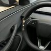 Interior view of a Tesla steering wheel showing the leather grip and controls.