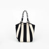 A black and white striped knitted tote bag with black leather handles.