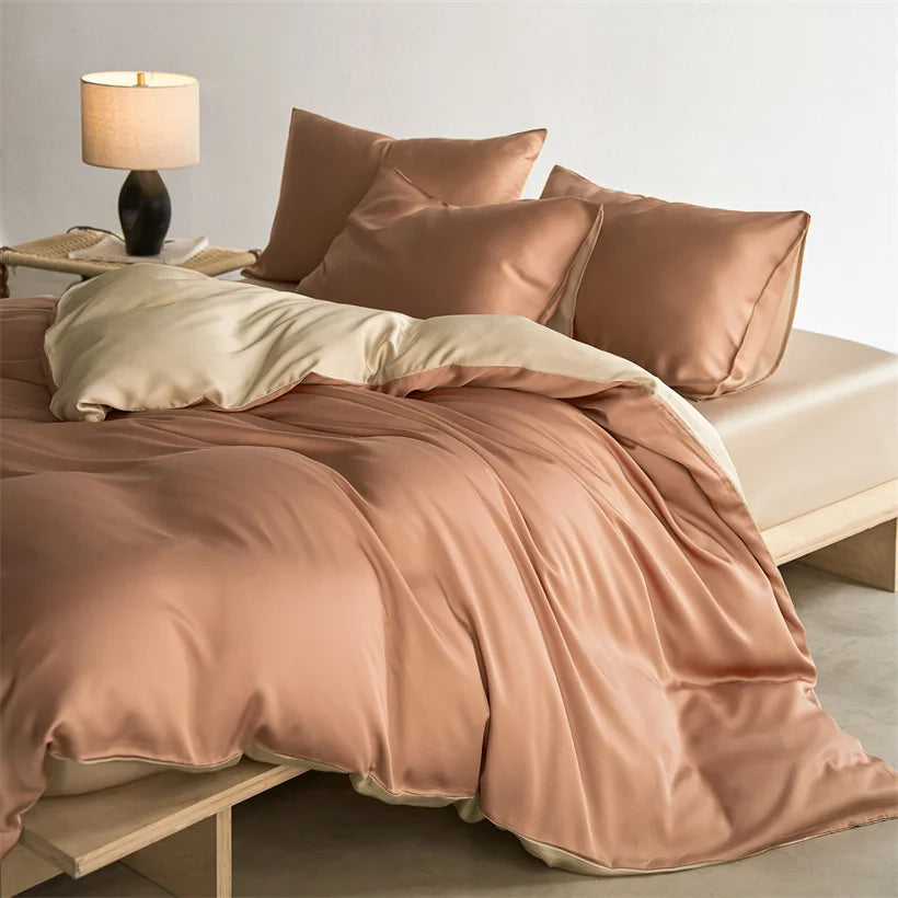 A luxurious rose gold duvet cover set with soft folds on a bed, next to a table lamp.