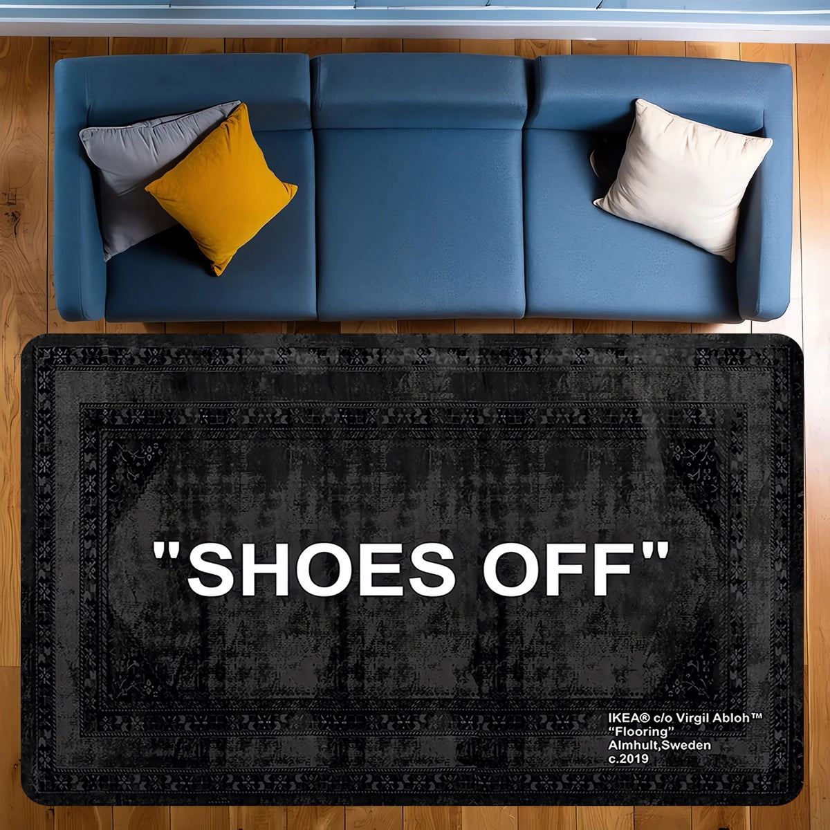 A dark gray doormat with the text SHOES OFF placed on a wooden floor.