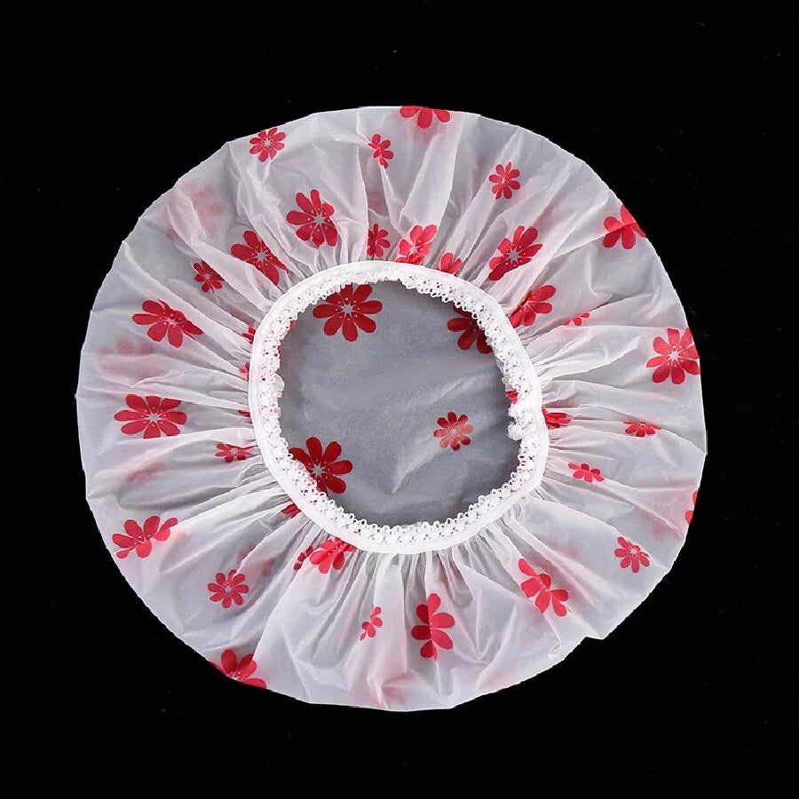 A white sheer shower cap with a pink background and red floral patterns.