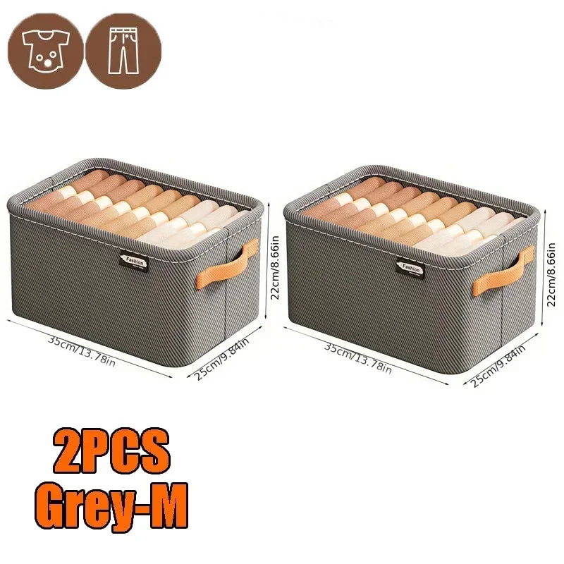 Zwei graue Stoffkisten für Kleiderschränke mit Holzständern und einem kleinen Kleidungsstück.