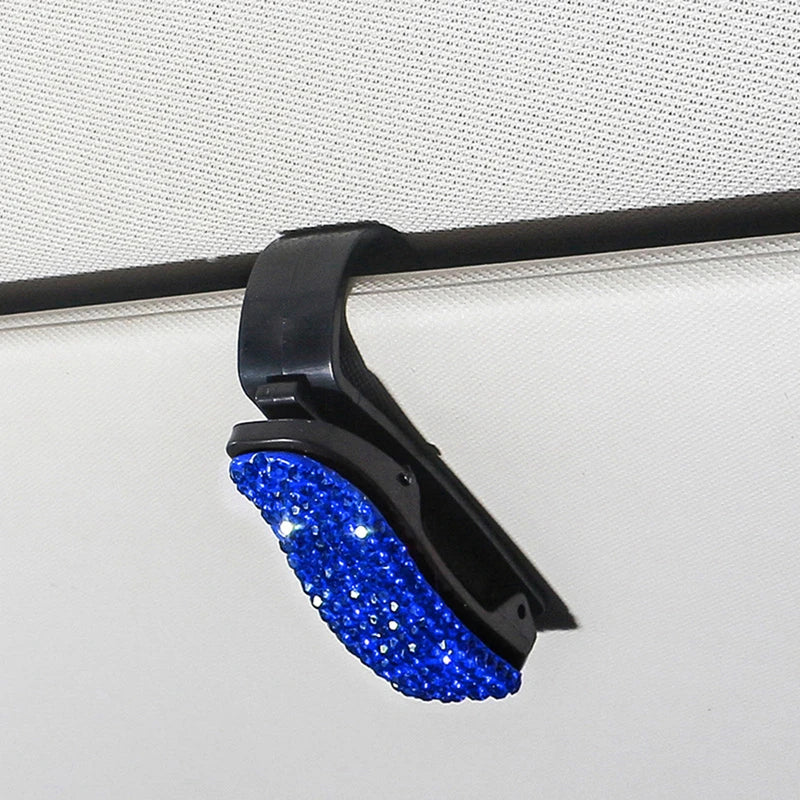 Black clip with blue crystal rhinestones used to secure sunglasses on a visor.