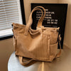 A tan corduroy tote bag with a drawstring closure and adjustable strap is displayed on a light surface.