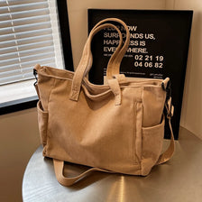 A tan corduroy tote bag with a drawstring closure and adjustable strap is displayed on a light surface.