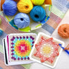 A collection of colorful crochet square pattern cards and yarn balls are displayed on a light surface.