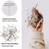 A hand holds a bundle of T-shaped metal pins used for knitting, sewing, and crafting.