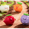 A collection of hand-painted resin vegetable figurines in various colors like yellow, orange, red, and purple placed in brown