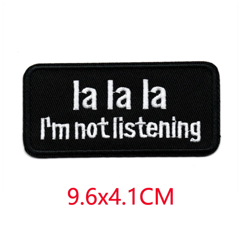 Black embroidered iron-on letter patch with white text that reads I'm not listening