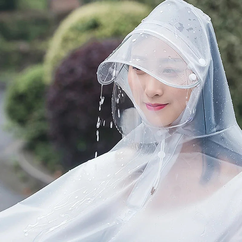 A woman wearing a transparent waterproof motorcycle rain poncho with a hood, with water dripping down the fabric.