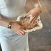 A person holds a white sequin beaded chain shoulder clutch bag in their hand.