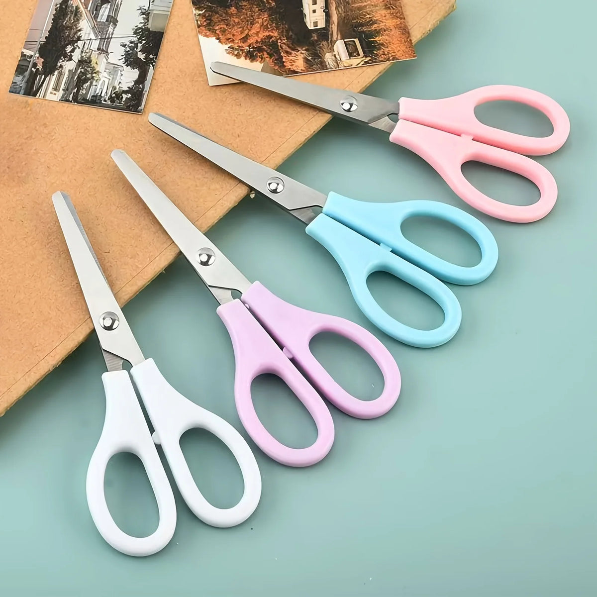 A set of five precision stainless steel scissors in pink and light blue colors resting on a brown paper background.