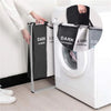 A person is loading a foldable waterproof laundry basket with handles and sorting compartments into a white washing machine.