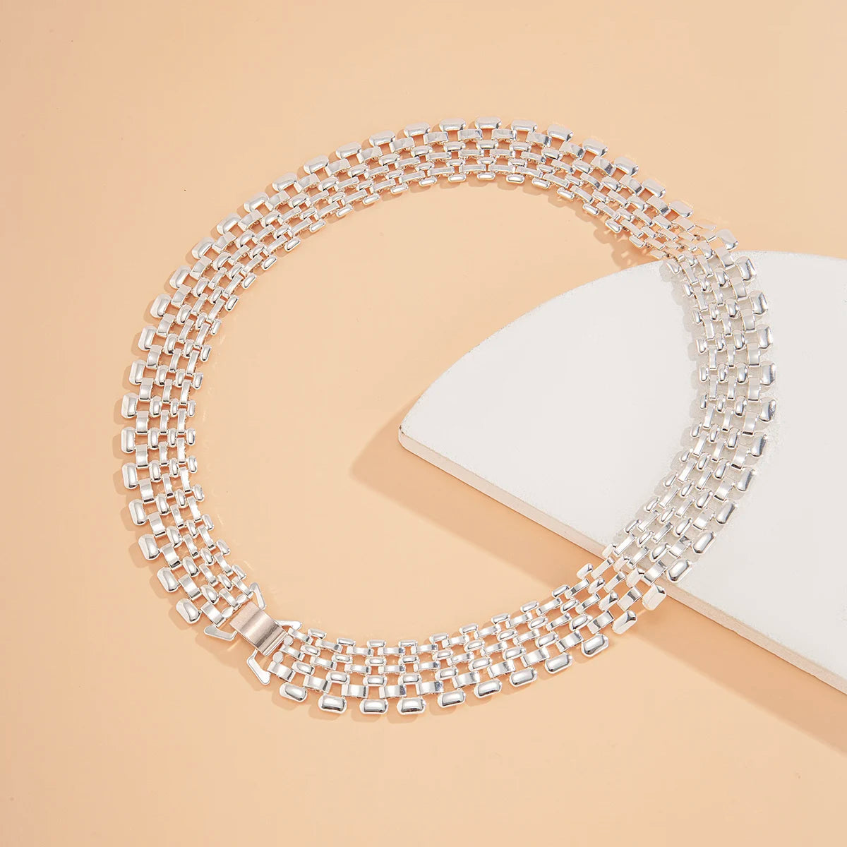 Set de collier et bracelet à maillons cubains argentés, sur fond clair.