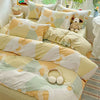 A set of beige and pale green cotton pillow shams and duvet covers displayed on a bed.