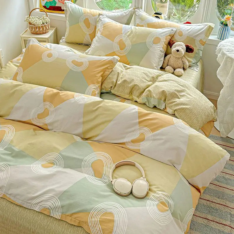 A set of beige and pale green cotton pillow shams and duvet covers displayed on a bed.