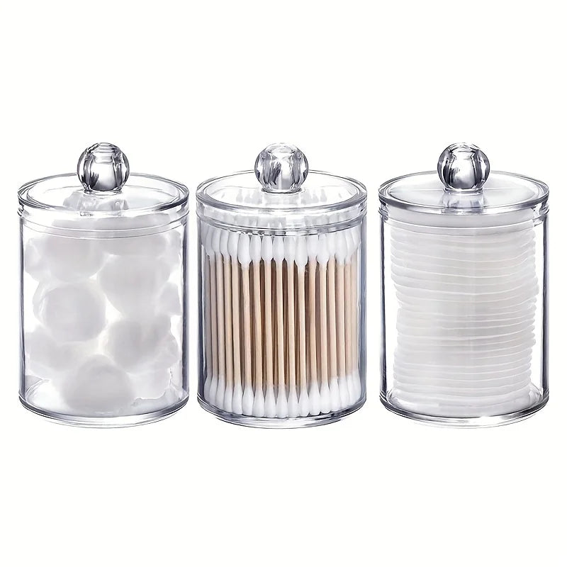 Three clear acrylic jars with lids holding cotton balls and swabs.