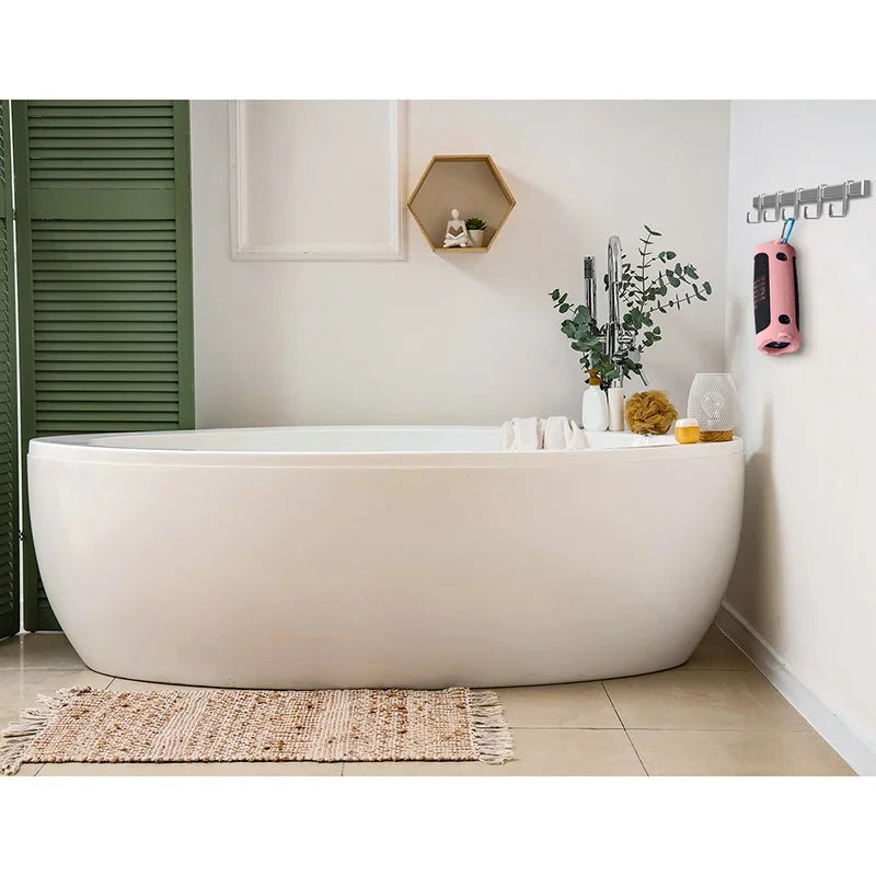 A white bathtub in a bathroom setting with a wooden shelf and a pink portable speaker mounted on the wall.