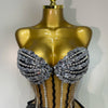A gold-toned mannequin displays a sparkly two-piece party outfit with a see-through top and black accents.