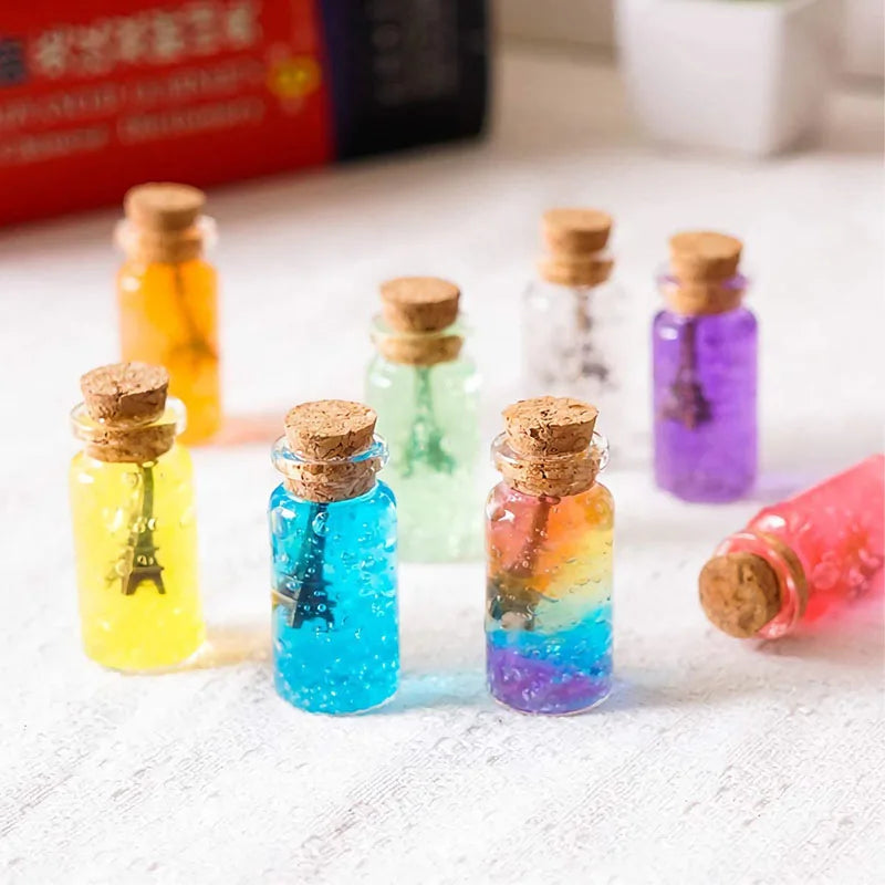 A collection of colorful mini glass bottles with cork stoppers arranged on a white surface.