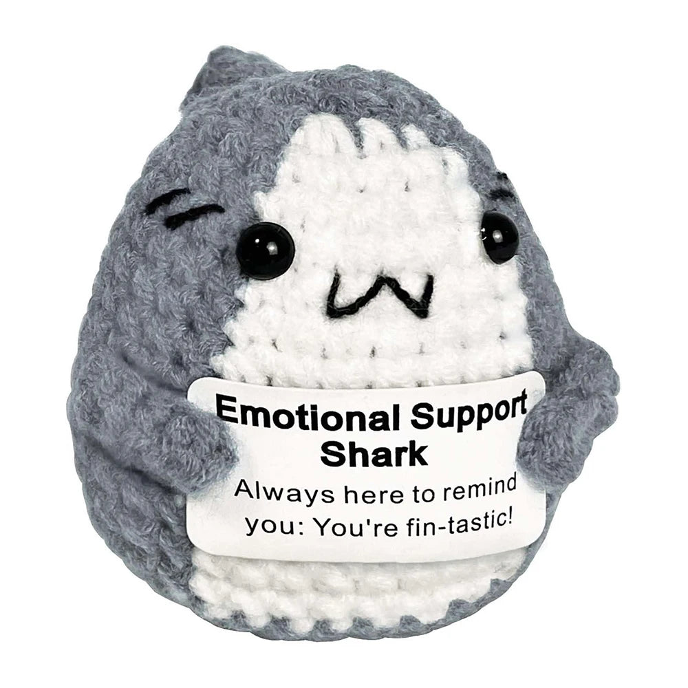 A gray and white crocheted shark plush ornament with a smiling expression.