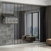 Interior design featuring black vertical slats and a rolled silver and black striped panel on a gray wall.
