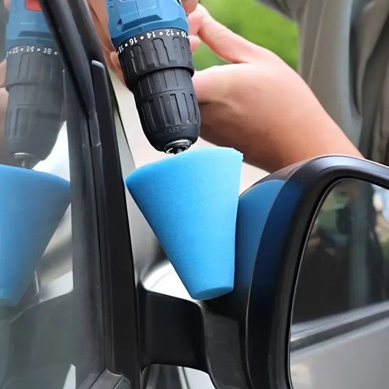 A hand is using a drill to apply a blue polishing sponge cone onto a car wheel for detailing.