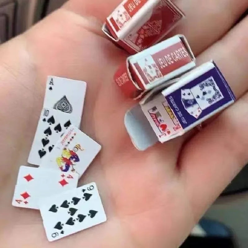 A hand holds several mini playing cards, including a deck and individual cards, for casual fun.