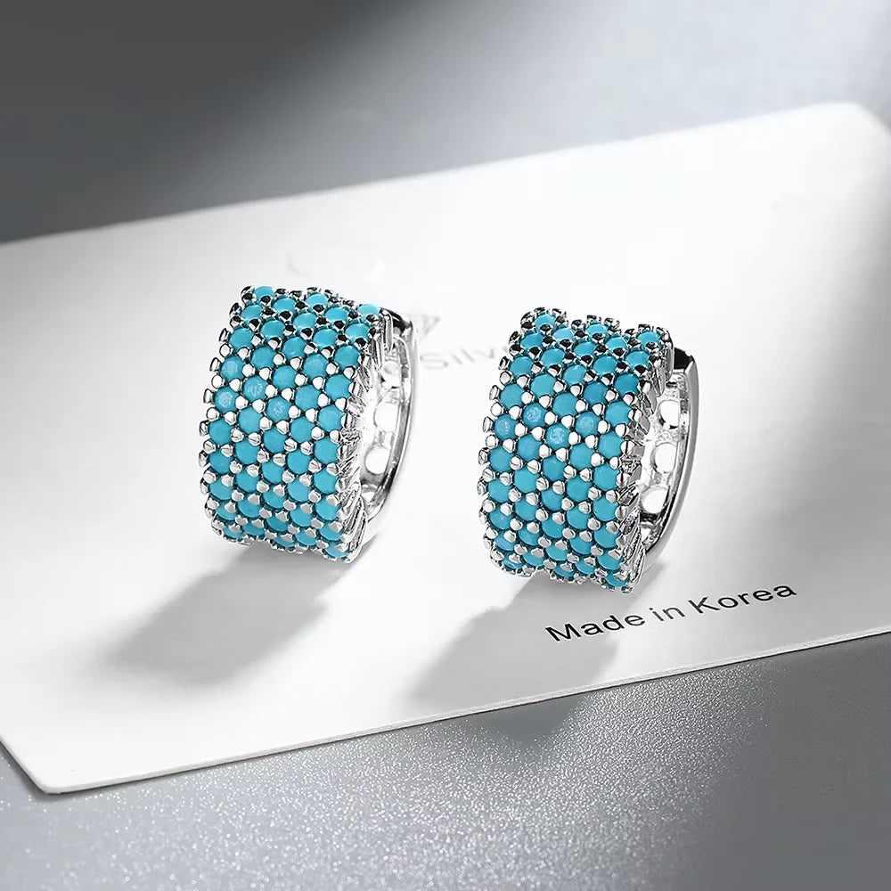 Pair of 925 sterling silver turquoise hoop earrings with a pave setting, displayed on a white card.