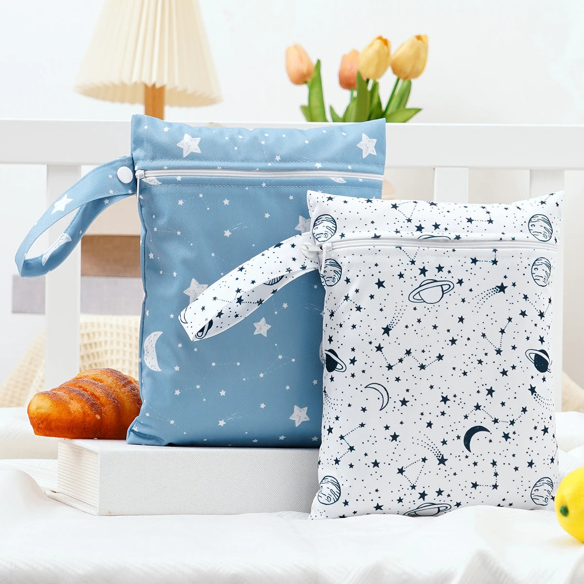 A pair of blue and white waterproof wet dry bags with star and celestial patterns are displayed on a white surface.