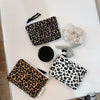 A leopard print cosmetic bag with a secure zipper and a matching fabric pouch are displayed on a white surface.