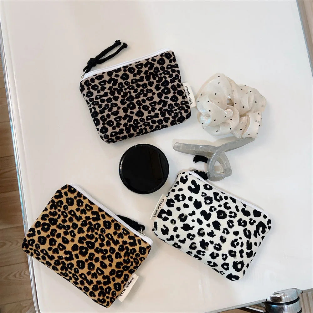 A leopard print cosmetic bag with a secure zipper and a matching fabric pouch are displayed on a white surface.