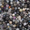 A close-up view of a mixed assortment of round glass beads in various shades of gray, purple, and black.