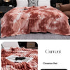 A cozy flannel fleece throw blanket in a cinnamon red tie-dye pattern draped over a sofa.
