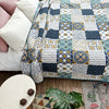 A pastoral patchwork cotton bedspread featuring blue, white, and yellow geometric patterns on a bed.