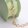 A light green flower-shaped bag features a gold chain extender and zipper detail.