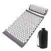 A dark gray acupressure mat and pillow set with numerous white dots for pain relief and relaxation.