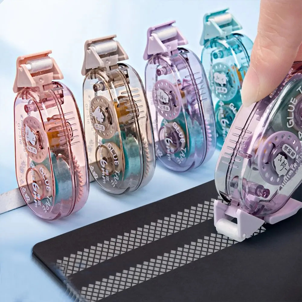A hand holds several double-sided adhesive tape rollers in various shades of pink and blue against a dark surface.