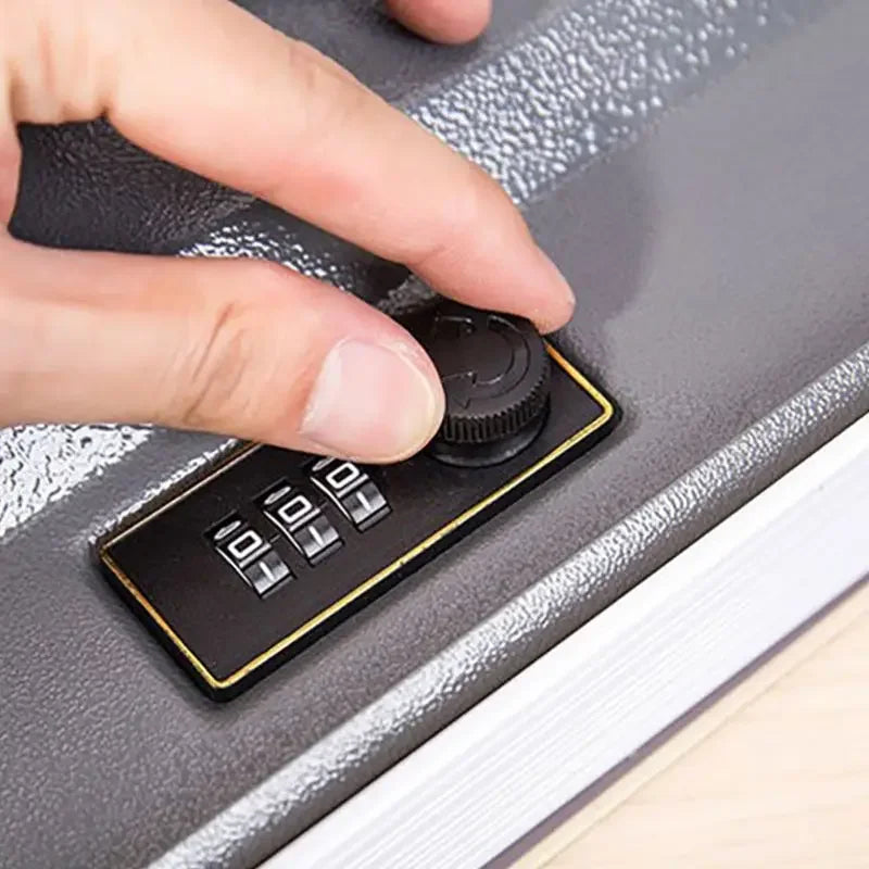 A hand is operating a black combination lock mechanism on a gray book safe.