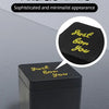 A black box with gold text that reads Just bow you is shown on a gray surface.