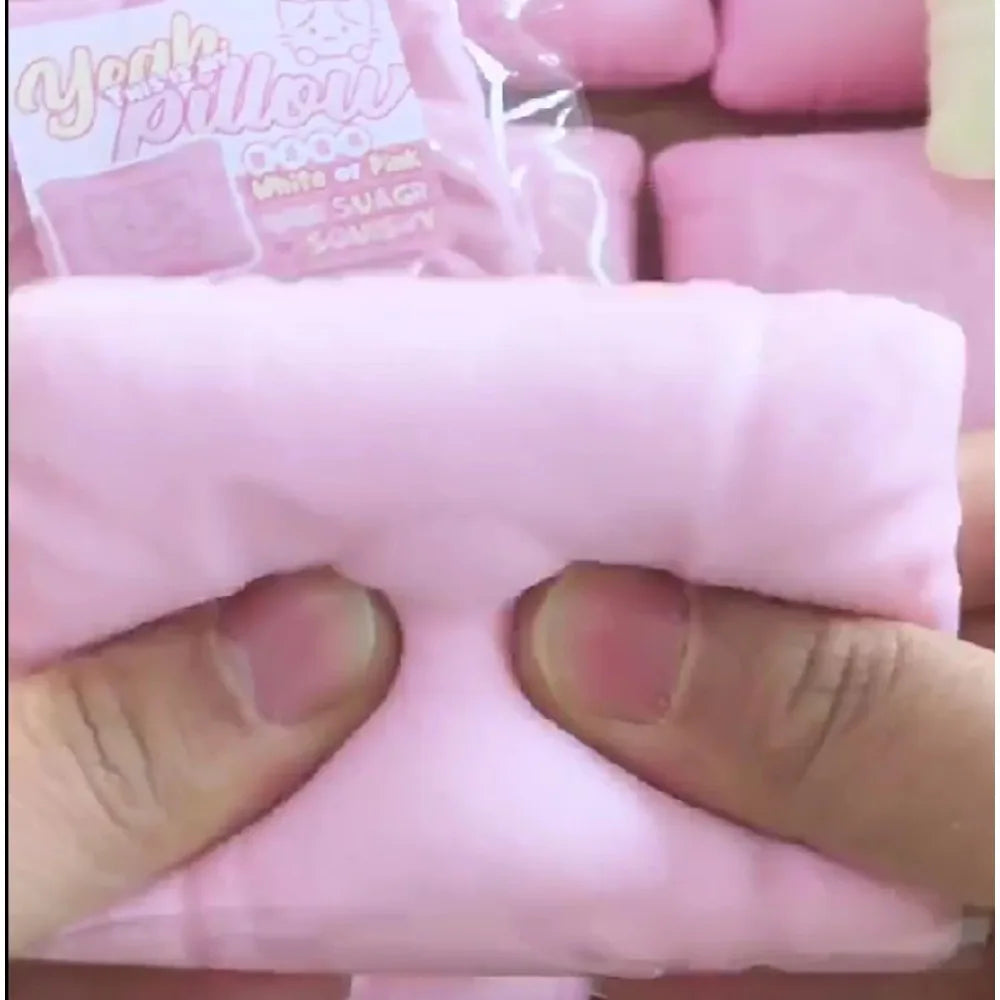 Une main tient un oreiller anti-stress rose en forme de chat doux.