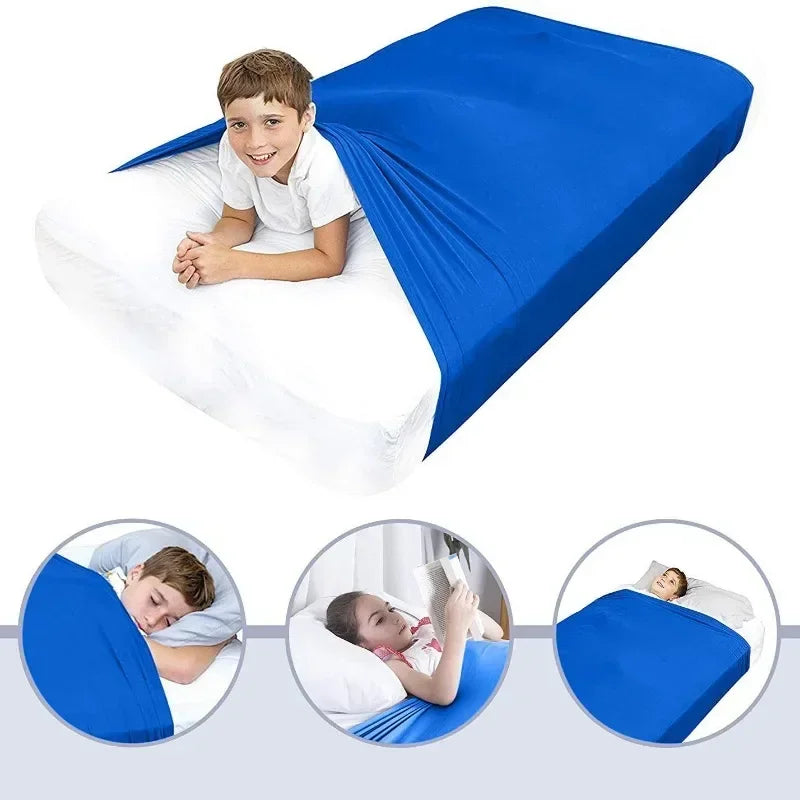 A boy is lying on a blue breathable stretchy sensory bed sheet for restful sleep.