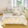 A white duvet cover set with a floral tea pattern featuring green and beige tones displayed on a bed.
