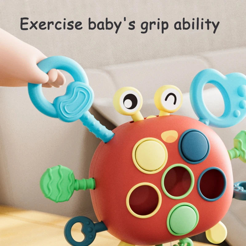 A silicone pull string sensory toy for babies with colorful grips and rings being held by a hand.